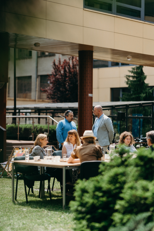 grupa ludzi przy stołach z poczęstunkiem na zewnątrz