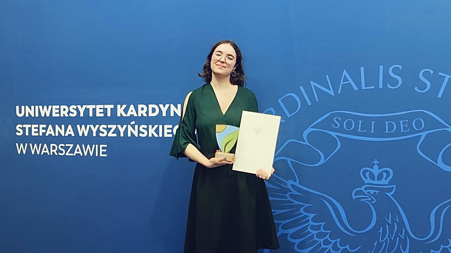 Osoba pozująca do zdjęcia z nagrodą w ręku