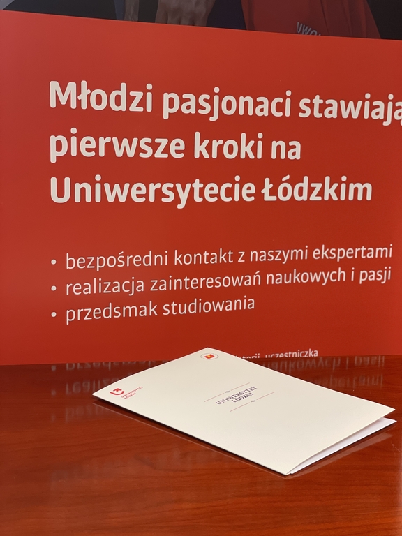 Na tle banneru projektu Zdolny uczeń świetny student zrobione zdjęcie białej teczki
