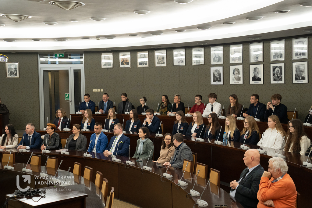 Grupa uczniów i wykładowców w auli akademickiej.