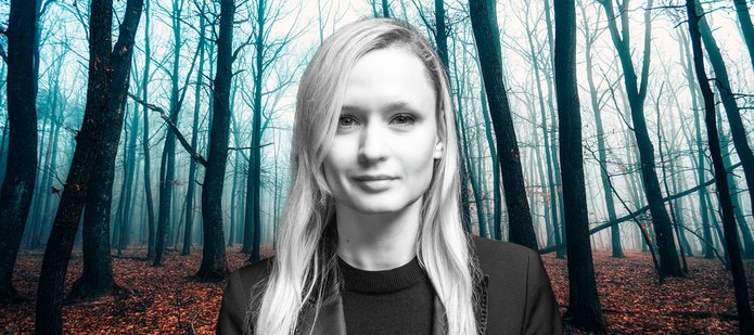 Dr Marta Jabłońska na tle lasu rozświetlonego jasnoniebieskim światłem