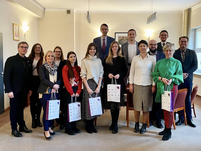 Grupa kobiet i mężczyzn pozuje do zdjęcia w pokoju dziekana WES