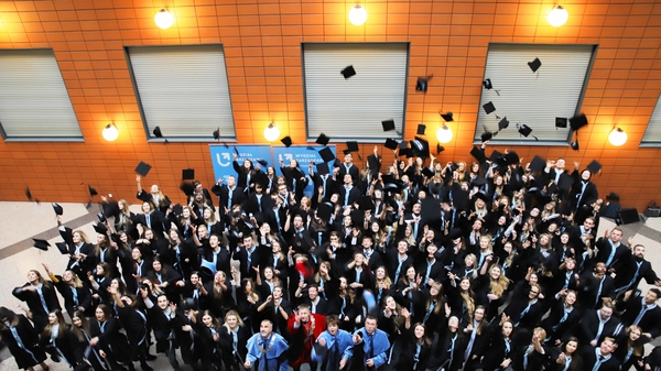 Podrzucanie biretów tłum absolwentów na patio podrzuca do góry birety