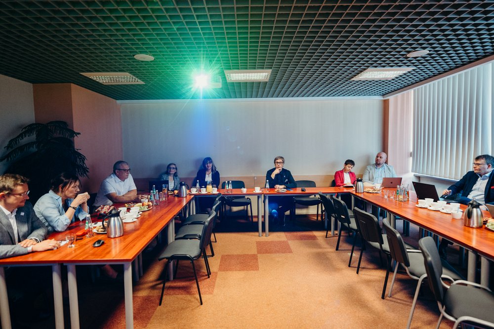 grupa ludzi siedząca przy stołach z poczęstunkiem