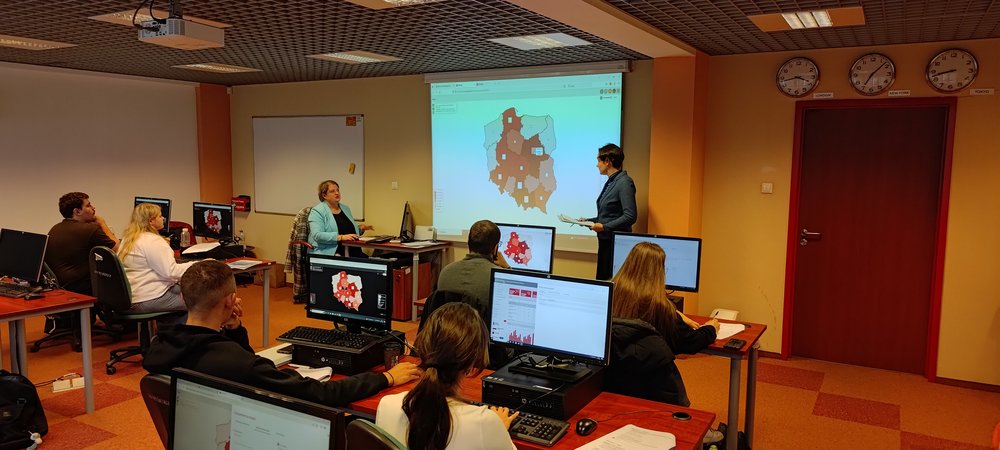 Prowadzące szkolenie prezentują na dużym ekranie dane z mapką wygenerowane w systemie Strateg; uczestnicy próbują zrobić to samo na swoich komputerach