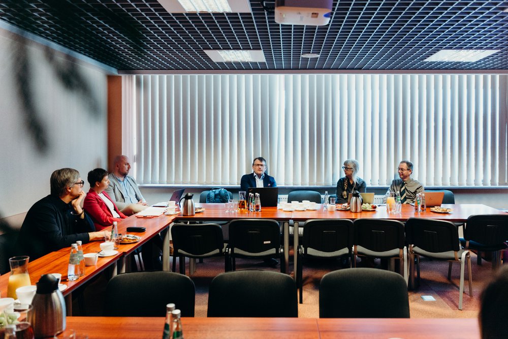 grupa ludzi siedząca przy stołach z poczęstunkiem