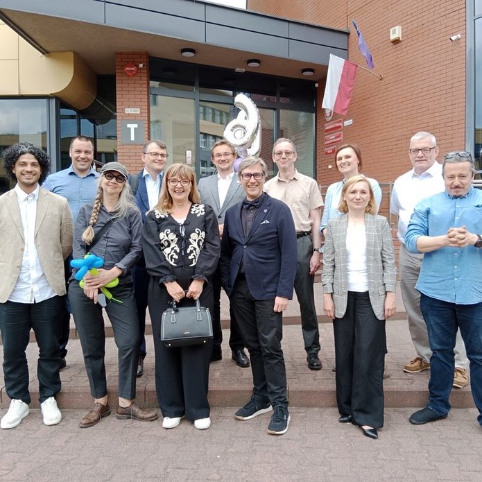 a group of smiling people in elegant clothes standing in front of the university building