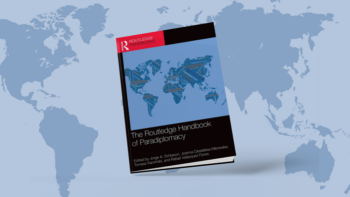 Okładka opisywanego wydawnictwa na tle mapy świata