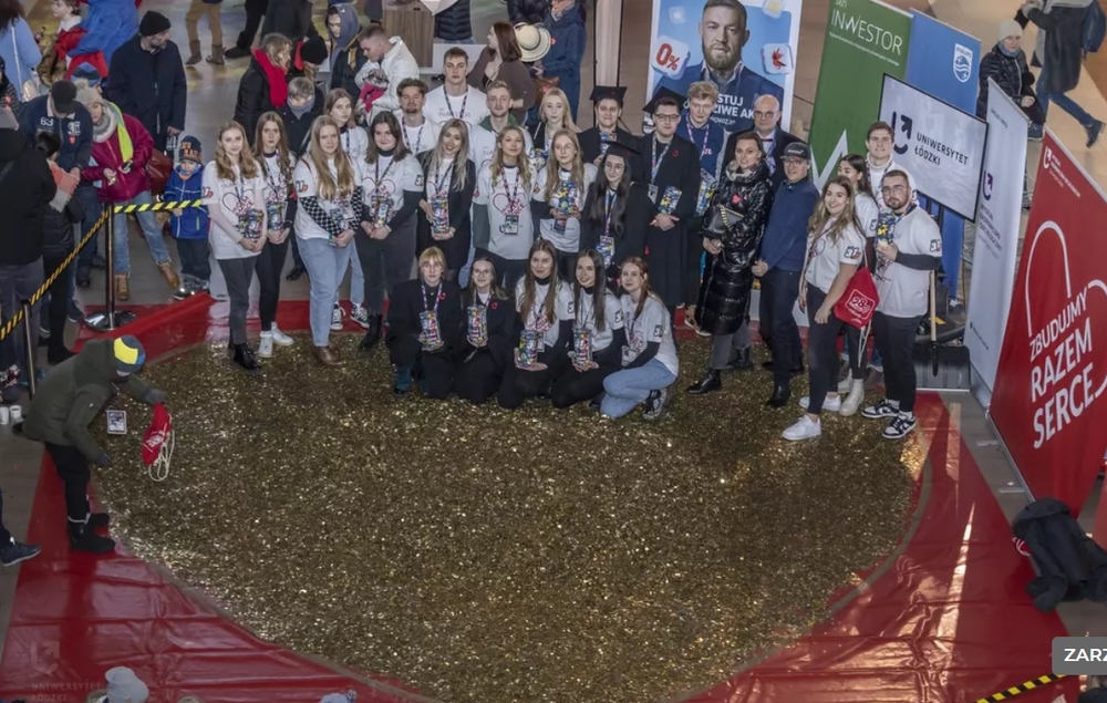 The University of Lodz students standing next to a huge heart made of gold coins The University of Lodz students standing next to a huge heart made of gold coins