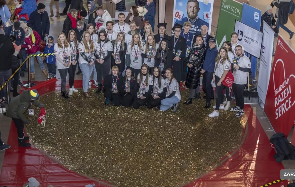 The University of Lodz students standing next to a huge heart made of gold coins 