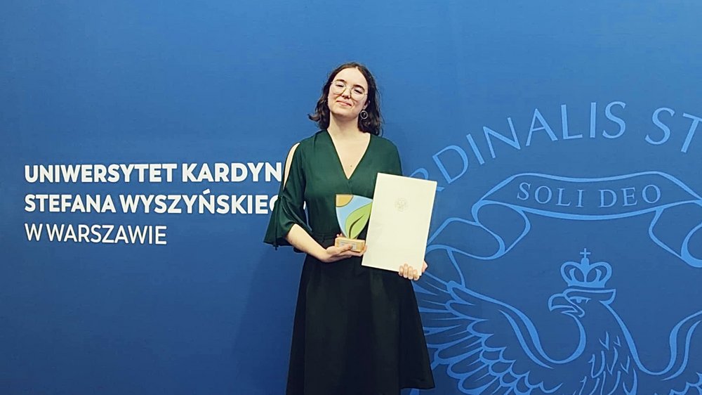 Osoba pozująca do zdjęcia z nagrodą w ręku