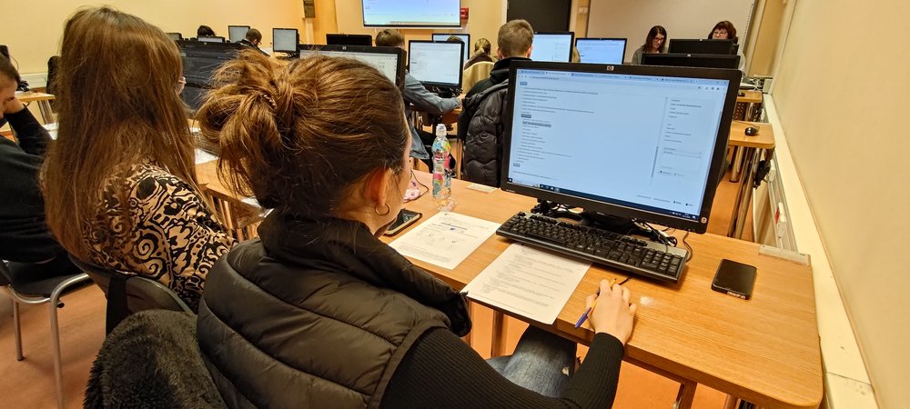 Dwie studentki siedzą przy komputerach i zastanawiają się jak rozwiązać zadania zlecone przez prowadzące