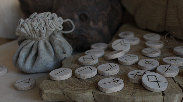 Worek, wokół którego leżą drewniane klocki z napisanymi znakami wikingów