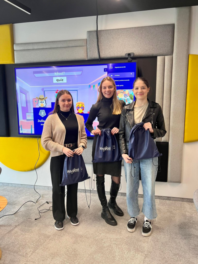 Trzy studentki stoją trzymając workoplecaki wygrane w quizie