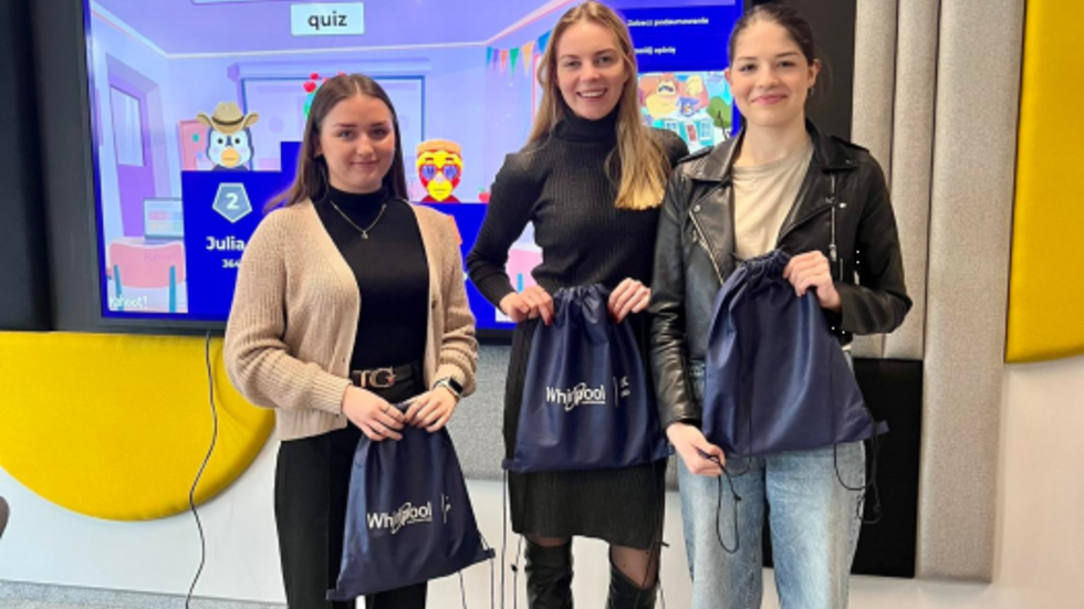 Trzy studentki stoją trzymając workoplecaki wygrane w quizie