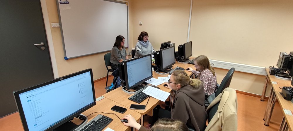 Dwie Prowadzące szkolenie siedzą za biurkiem i omawiają funkcjonalności Banku Danych Lokalnych GUS, a uczestnicy słuchają, wpatrując się w komputery