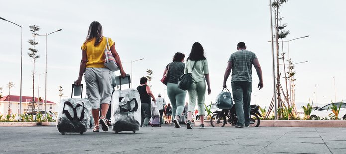 Ludzie z walizkami idący po parkingu