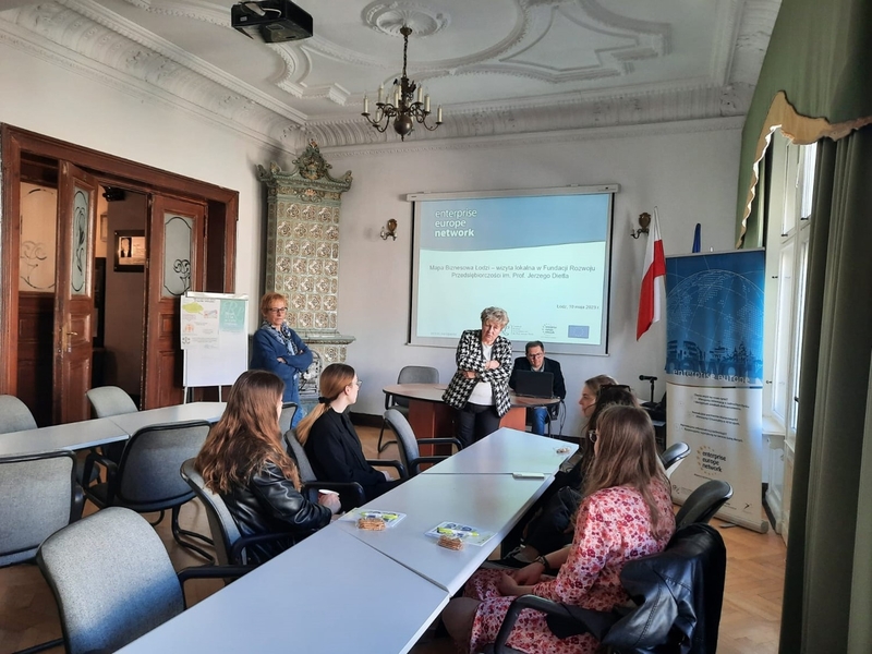 Mapa Biznesowa Łodzi - Wizja Lokalna - Fundacja Rozwoju Przedsiębiorczości 10.05.2023 - trójka prowadzących spotkanie rozmawia ze studentkami siedzącymi przy stole