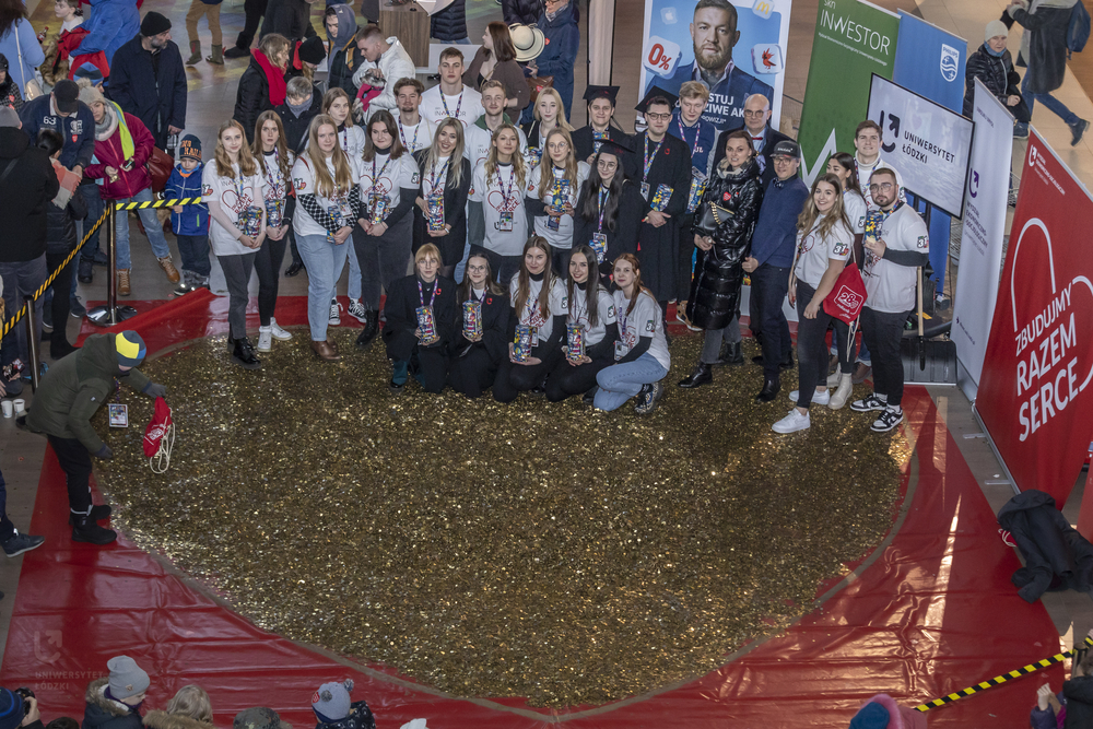 Studenci UŁ stojący przy wielkim sercu ułożonym ze złotych monet