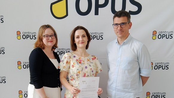 Trzy osoby trzymające dyplom